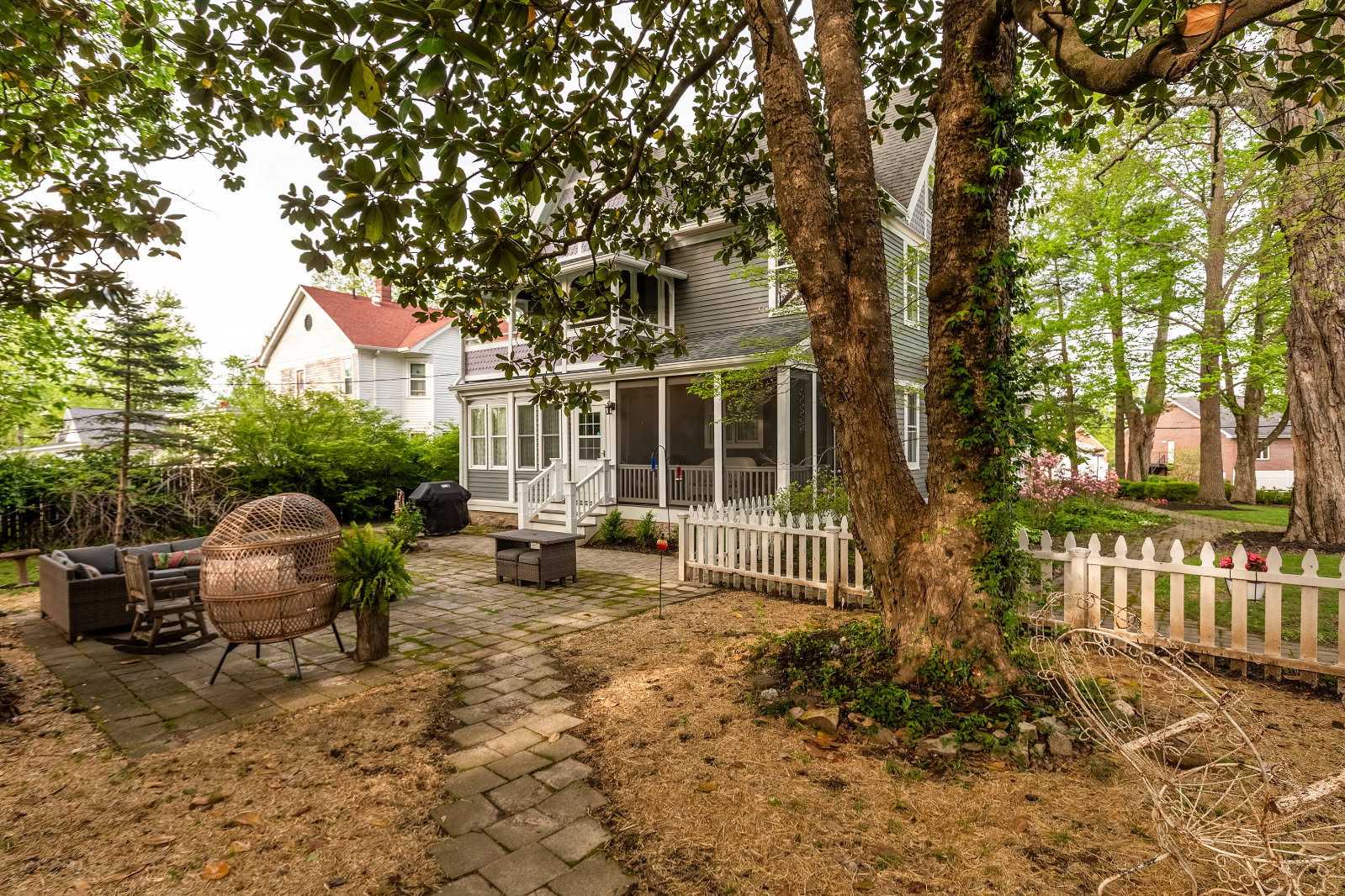 Outdoor yard with a fireplace and lawn furniture. House is in the background